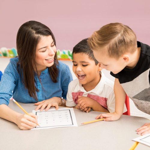 Good looking preschool teacher and students having a good time learning in the classroom
